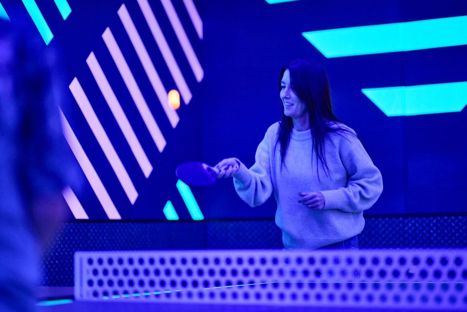 A close-up of a woman playing Glow Pong at Playxperience.