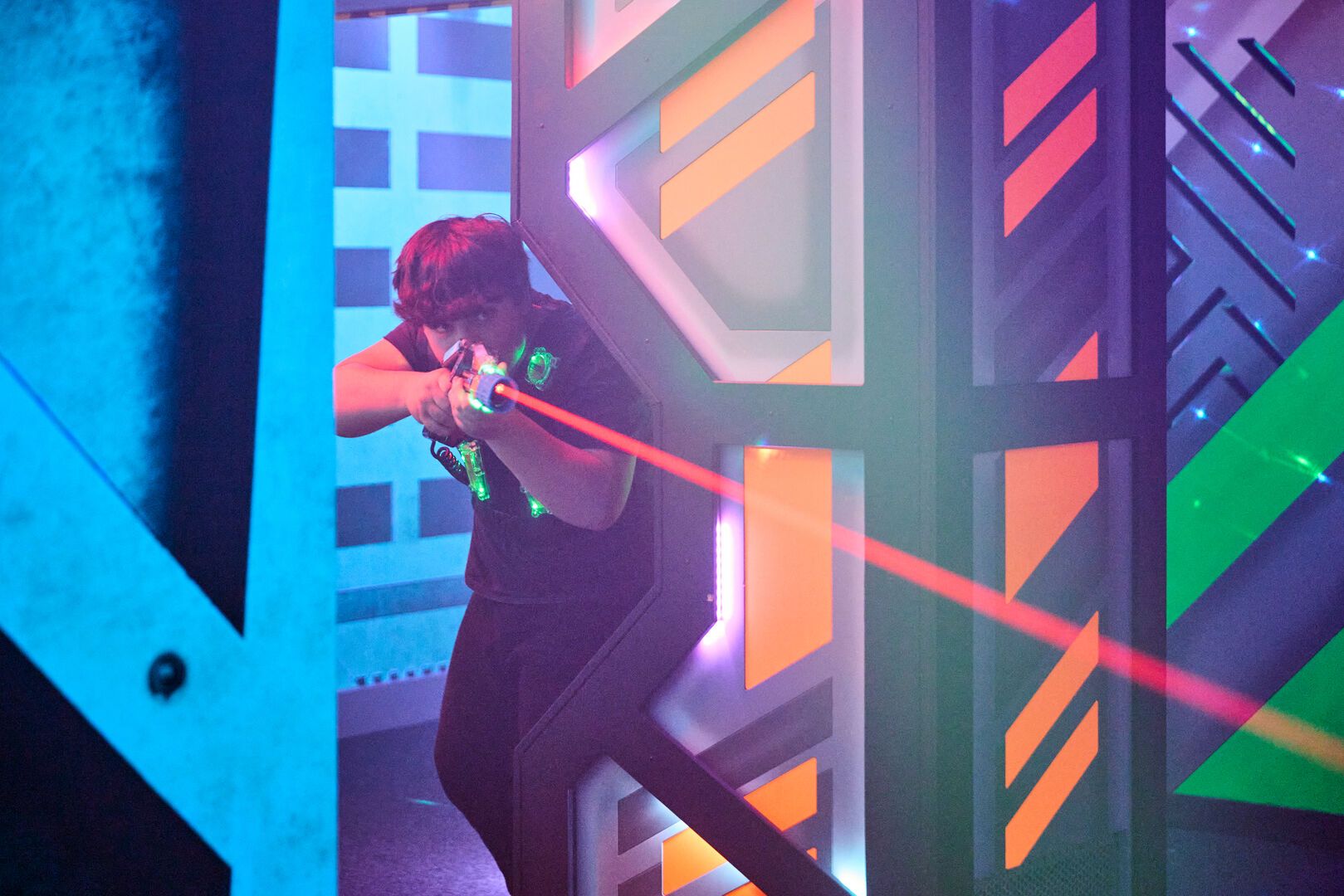 A photo of a young man aiming and firing his Laser Tag gun.