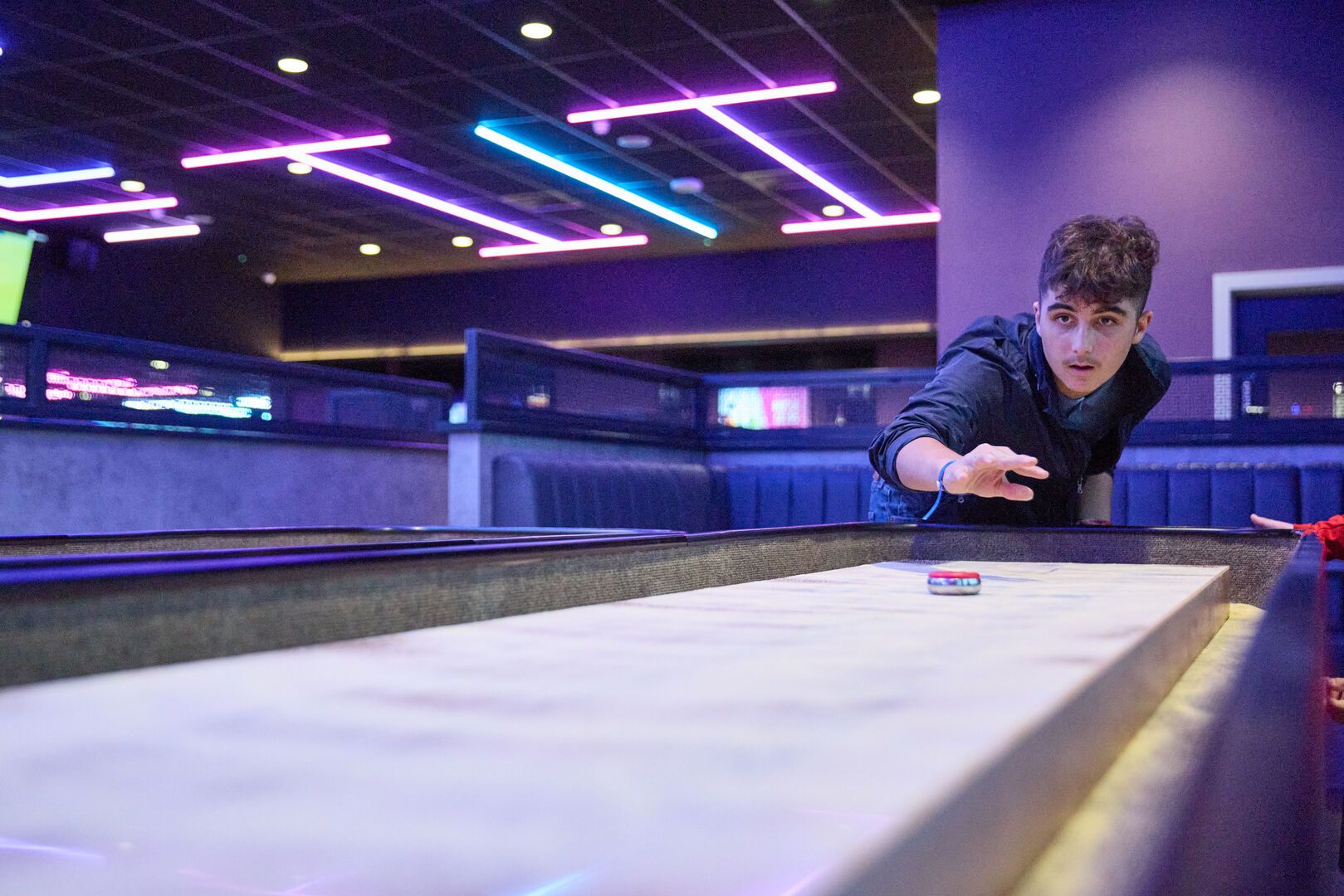 A guest plays Shuffleboard at Playxperience.