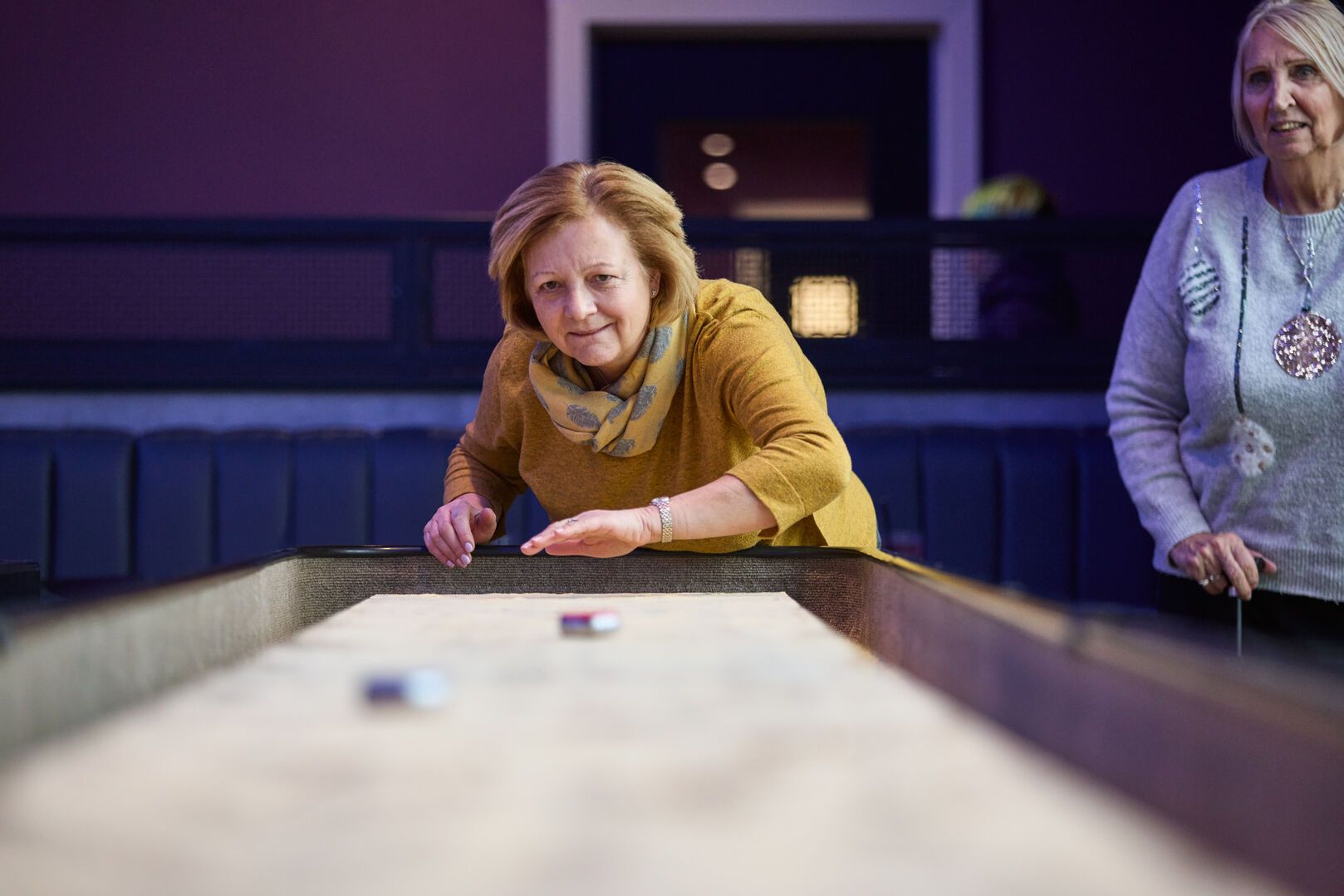 A close-up of a woman playing Shufflebard.