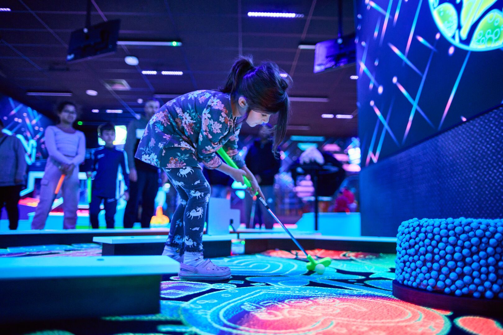 A young girl gets ready to hit the golf ball while playing Tech Putt.