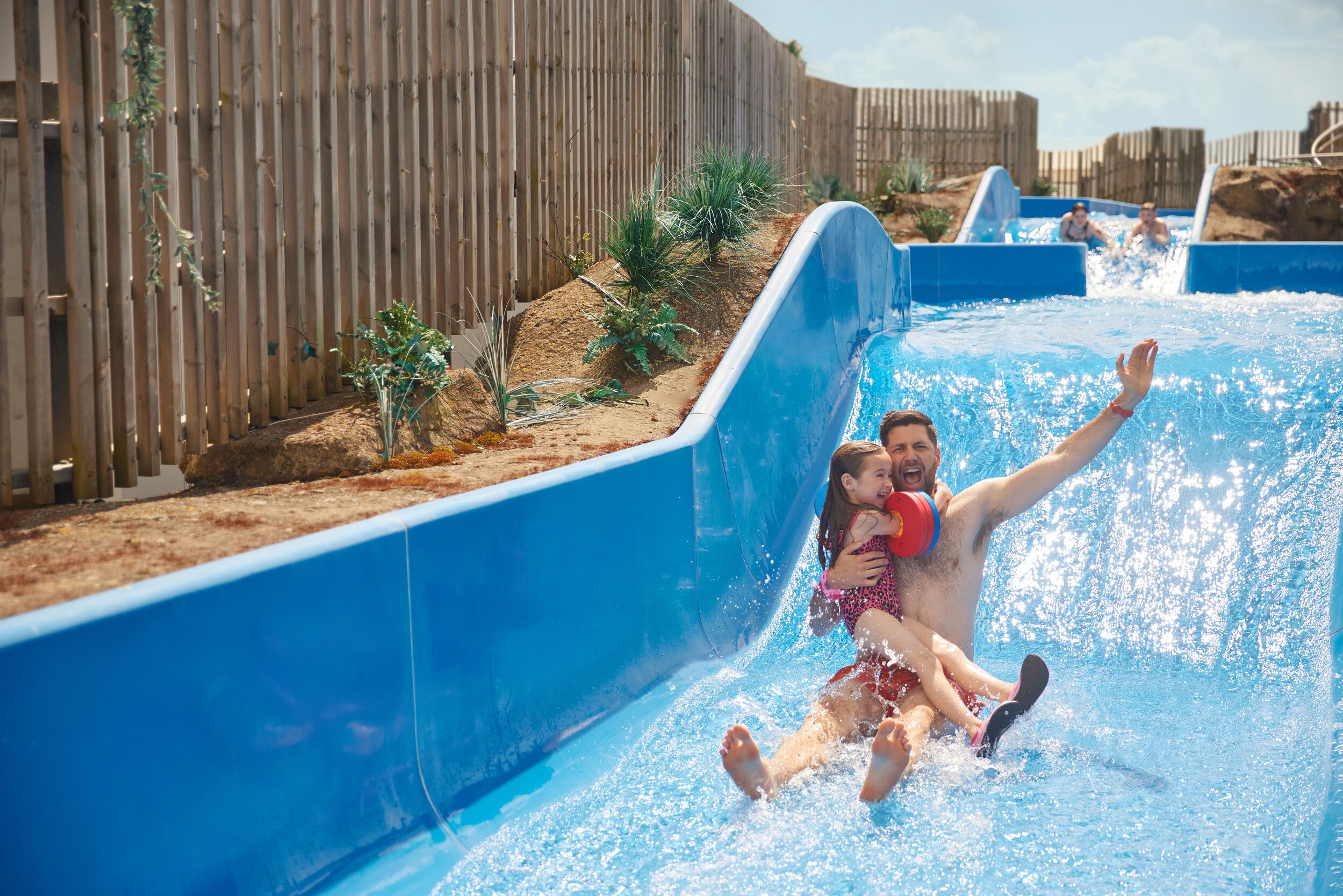 A father holds his daughter while going down the rapids.