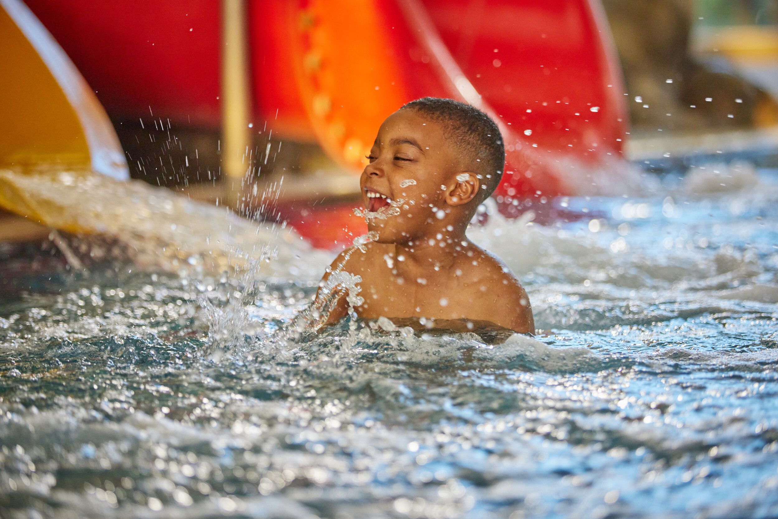 A boy playing in a pool beside the water slide.