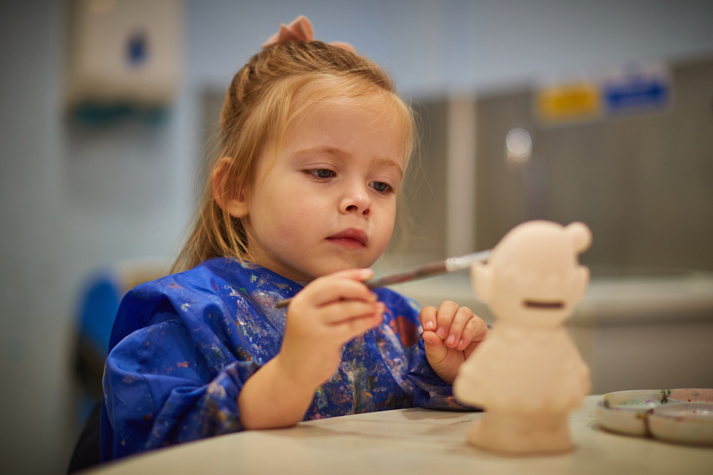 A little girl focused on pottery painting.