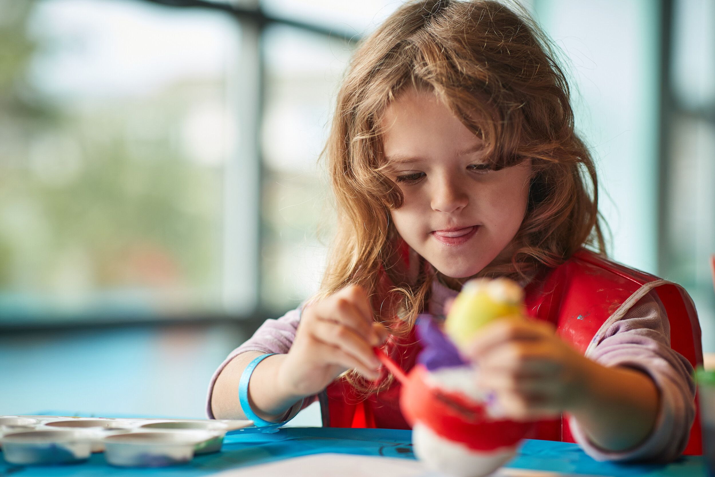 A little girl focused on pottery painting.