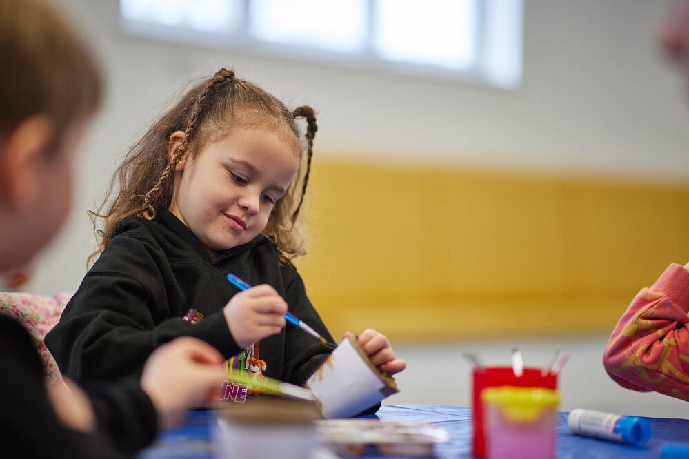 A little girl designing some art with paint brush.