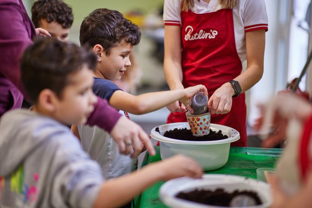 A boy putting soil in a pot at Potting and Planting.