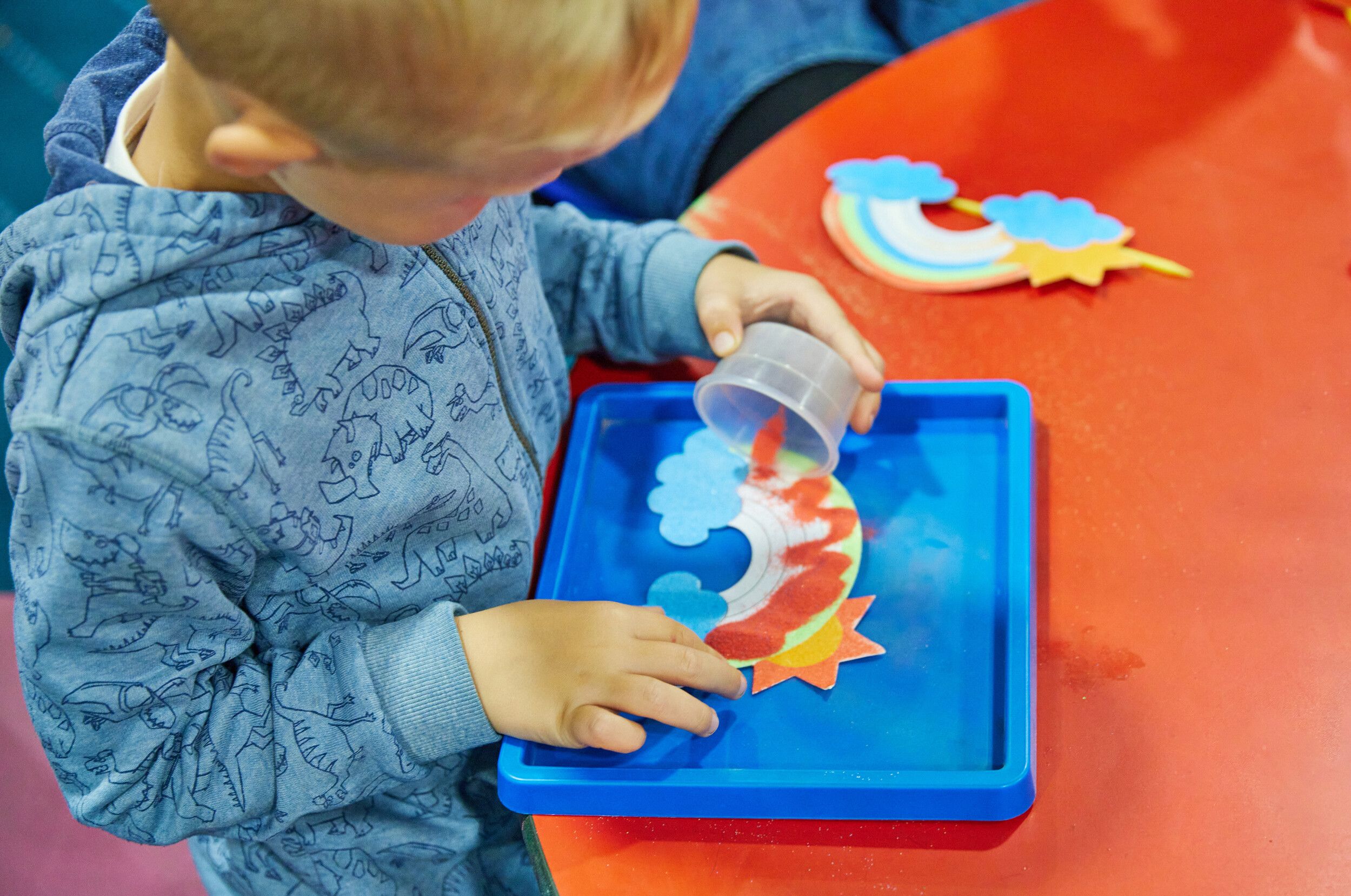 A little boy doing sand art using different colours.