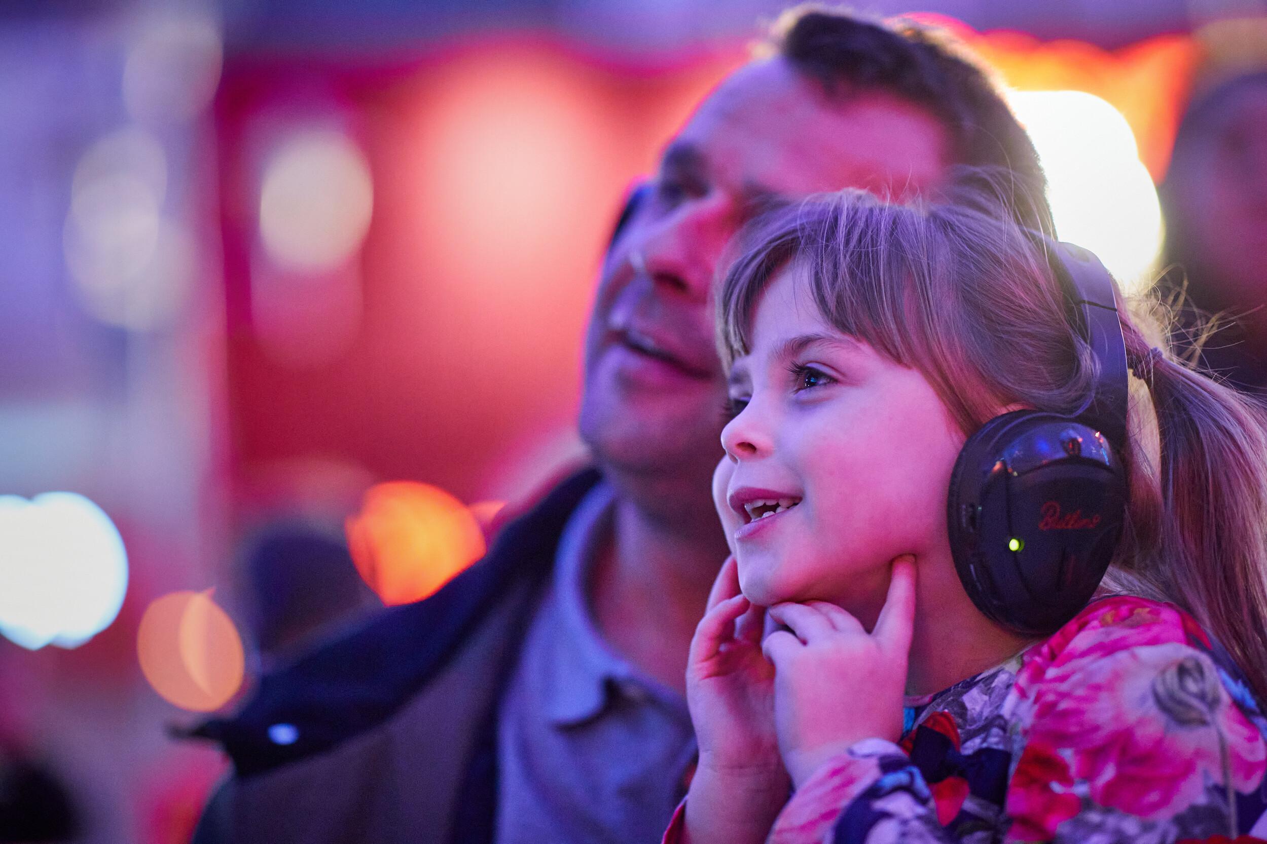 A man and a girl wearing headphones while watching in a silent cinema.