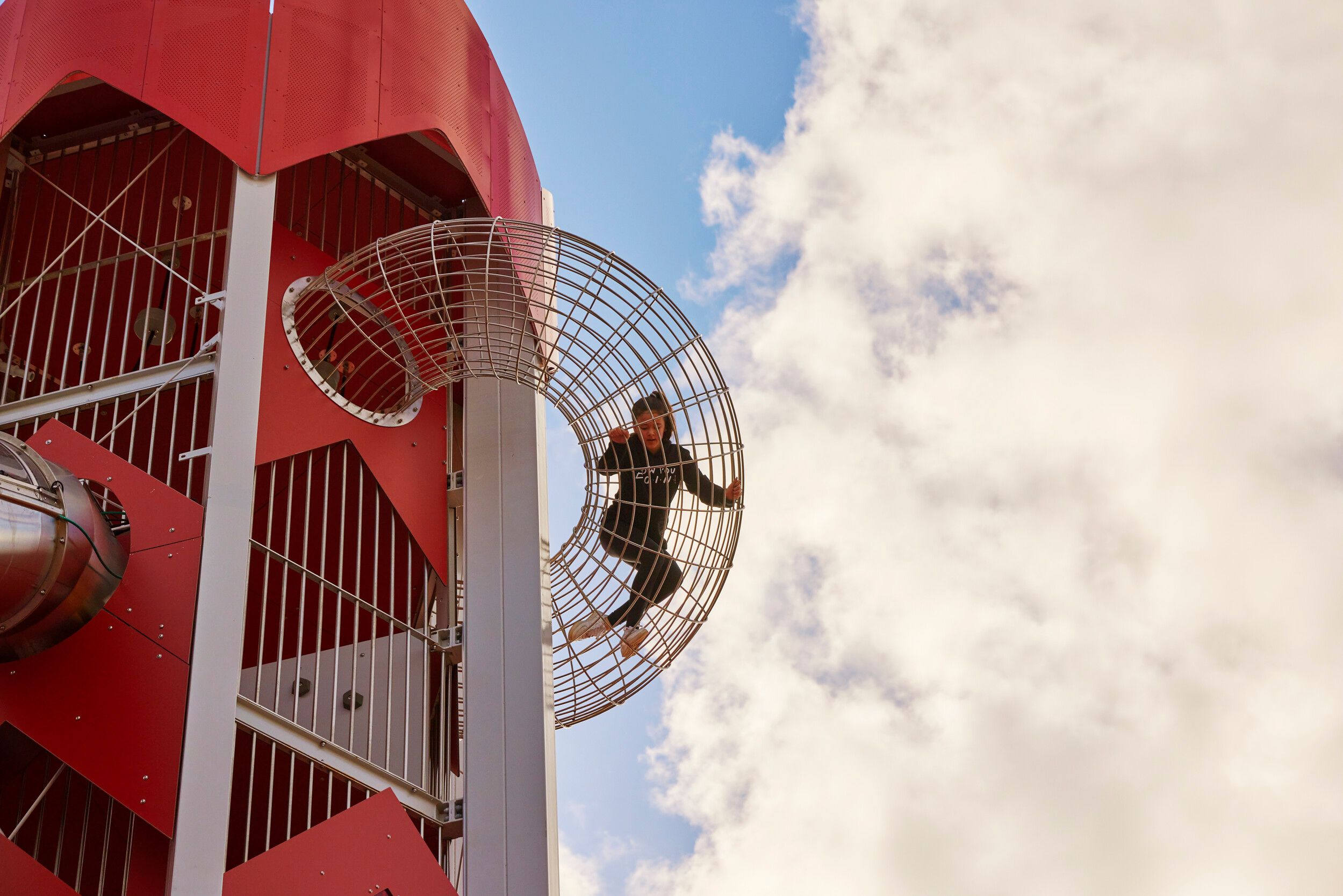 A girl playing in a red tower in Skypark.