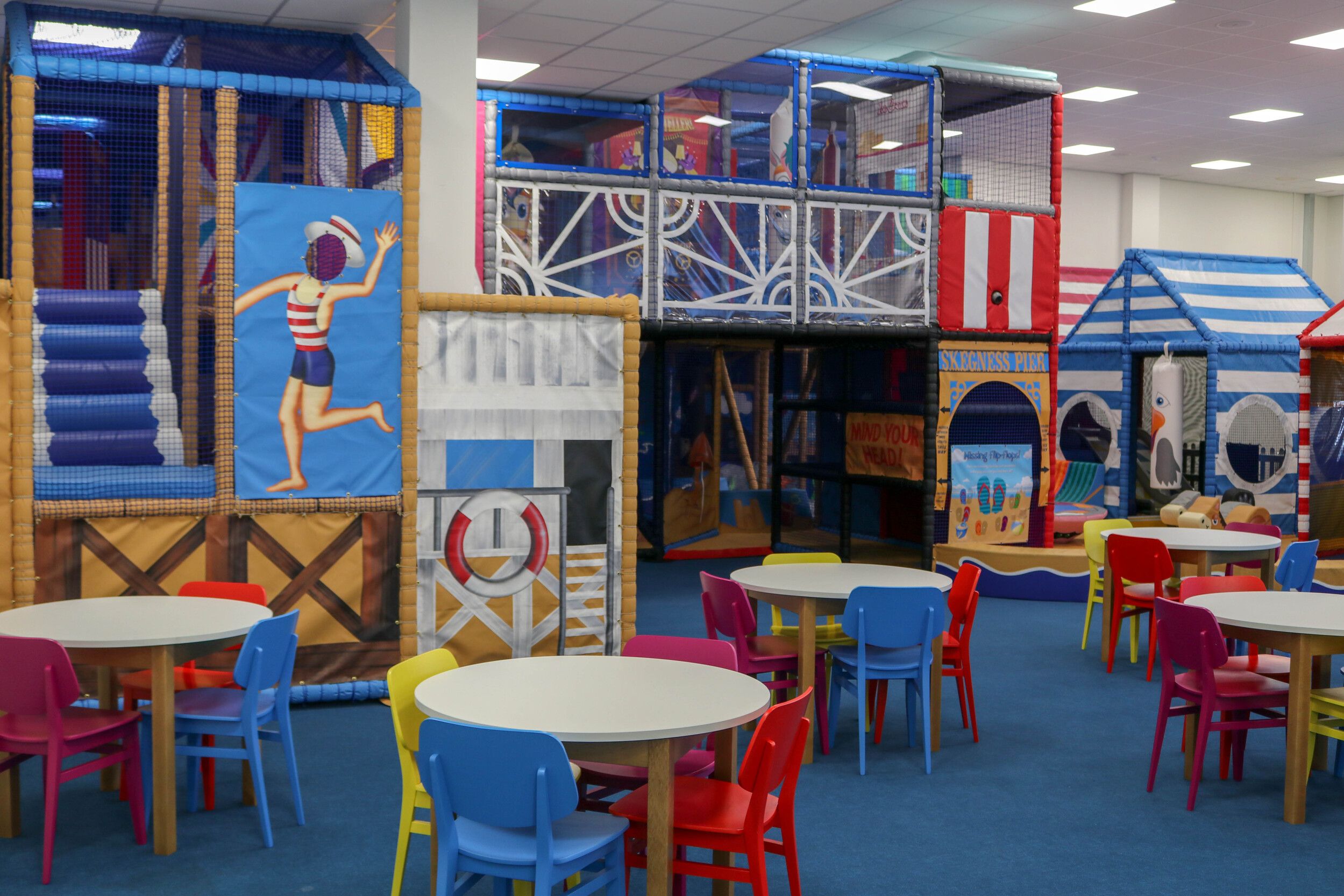 A colourful indoor play area with seat and tables,