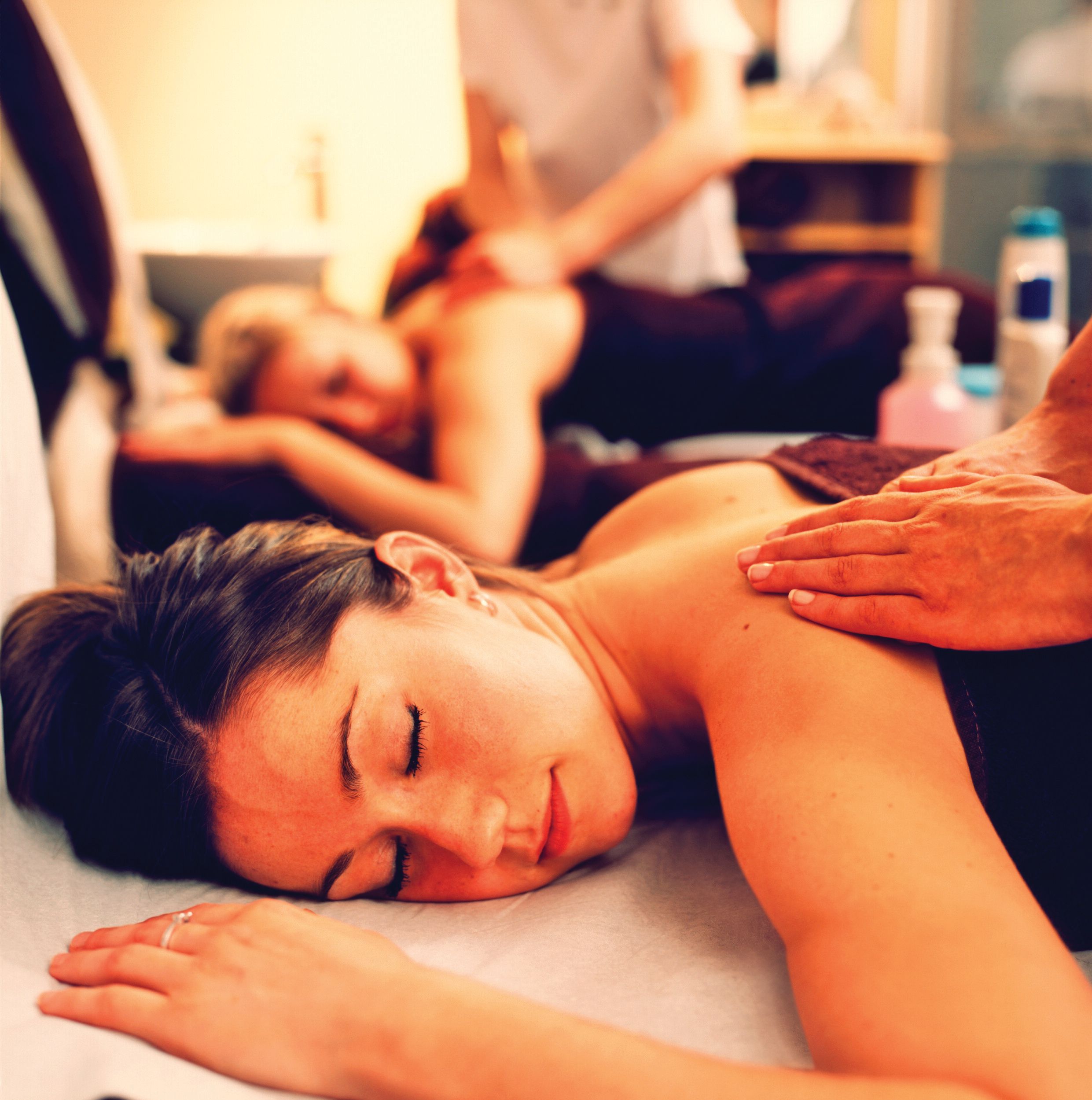 A woman in a prone position being massaged by a therapist.