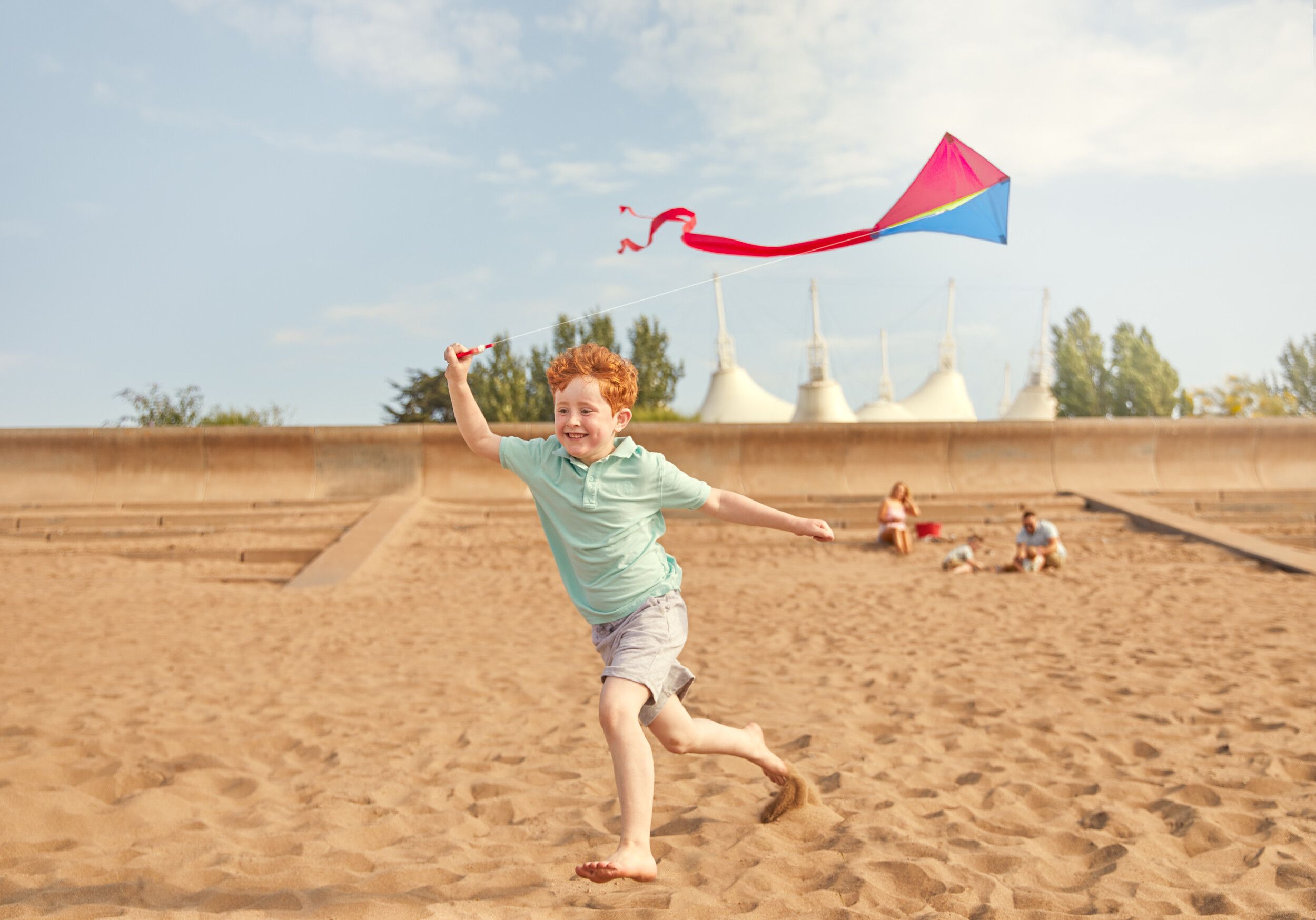 A boy playing with a kite on the beach.