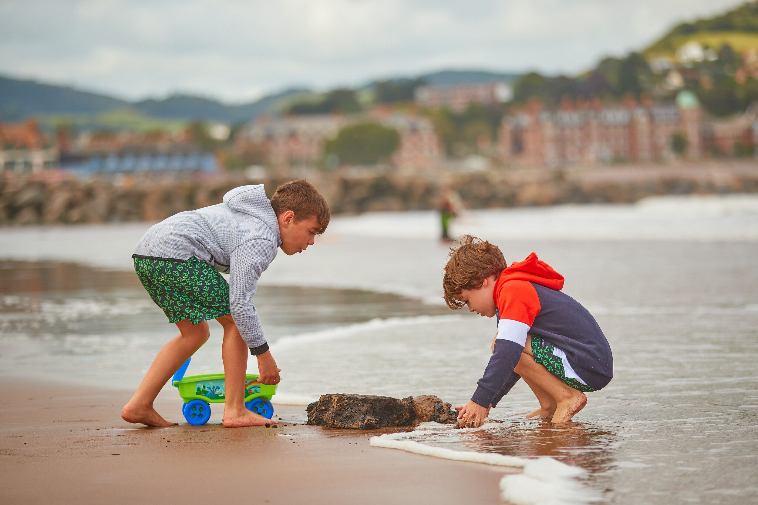 Two children playing with sand on the beach.