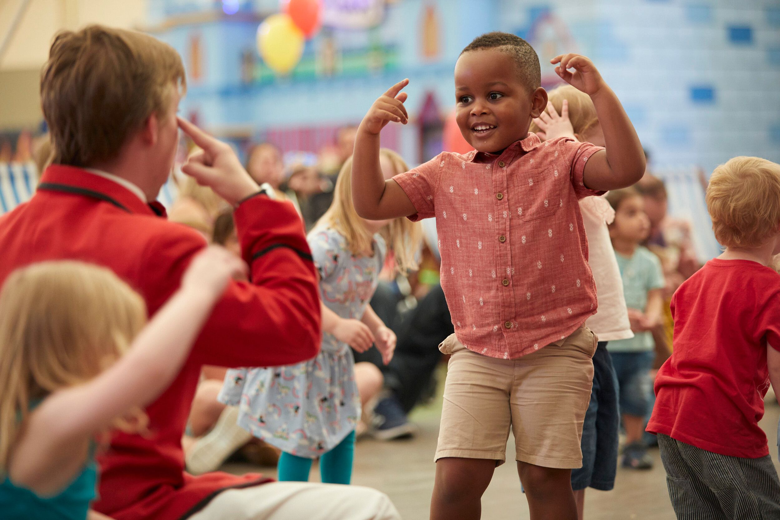 A staff teaching boy how to dance in Tots Disco.