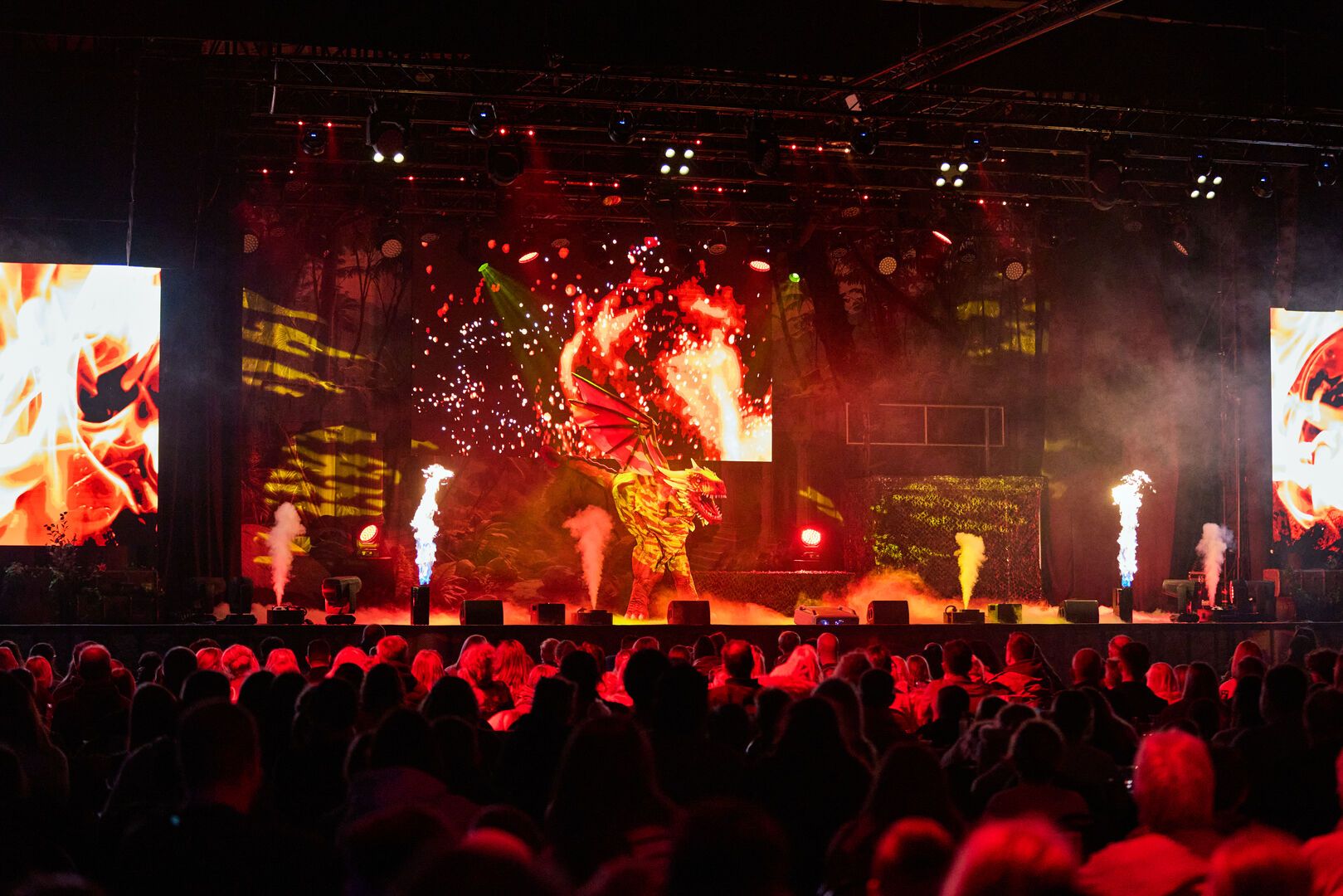 The audience watch the stage as a large man-made dragon stands in the centre of the stage, as part of the Animals and Mythical Beasts live show at Butlin's.