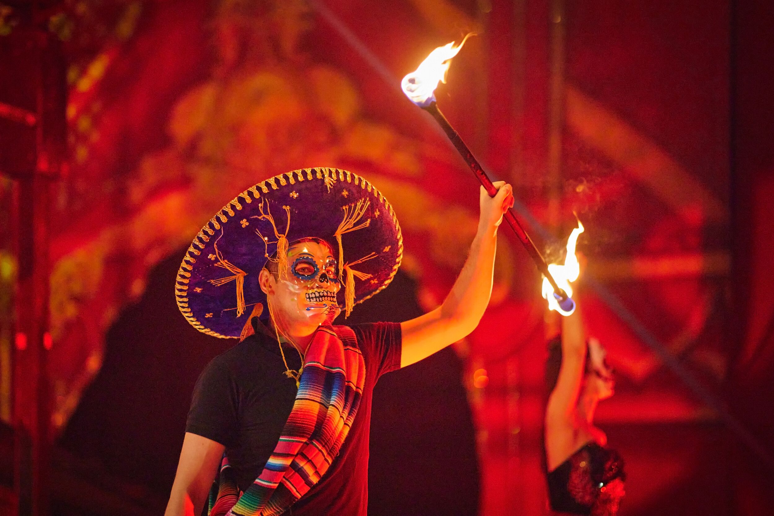 A man with a skeleton mask while holding a fire staff.
