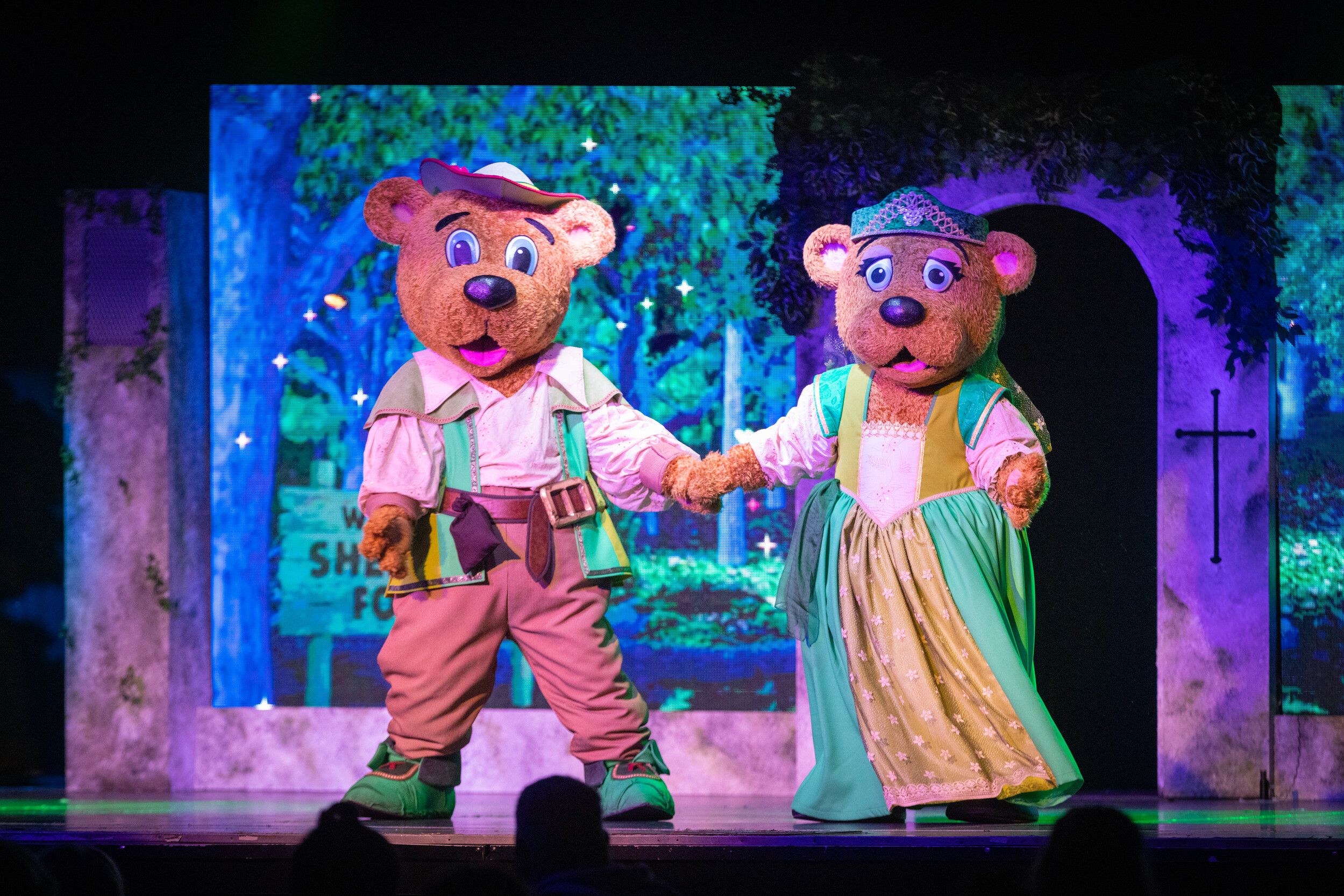 Billy Bear and Bonnie Bear holding hands on stage.