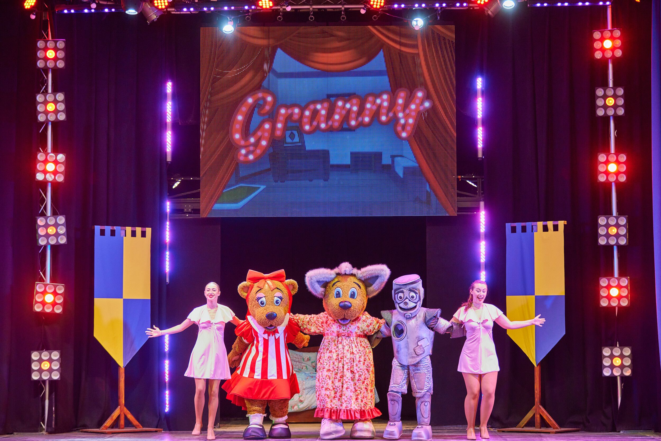 Billy and Bonnie Bear presenting on stage along with three performers.