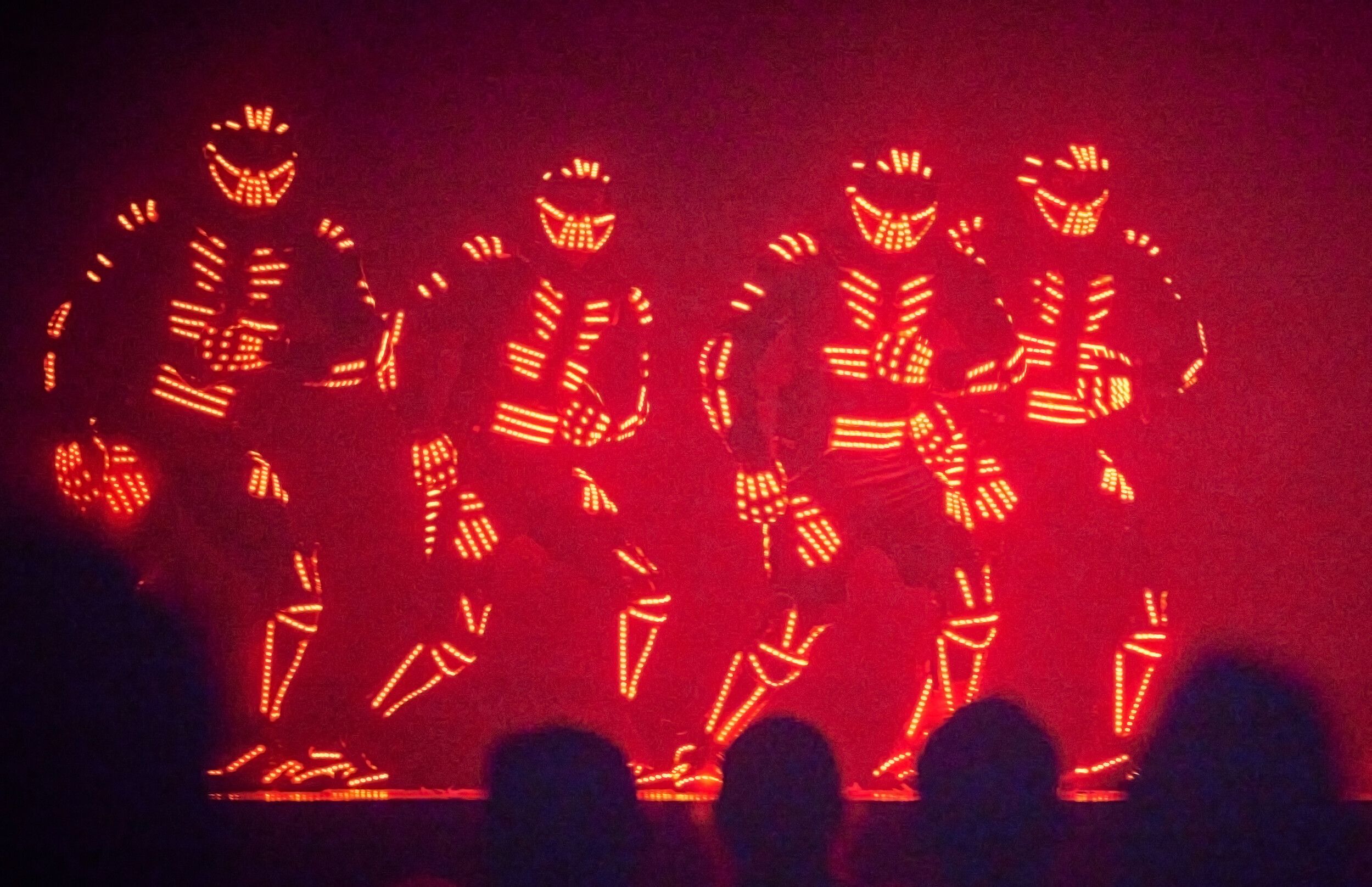 Four members of Electric City wearing LED costumes while performing on stage.