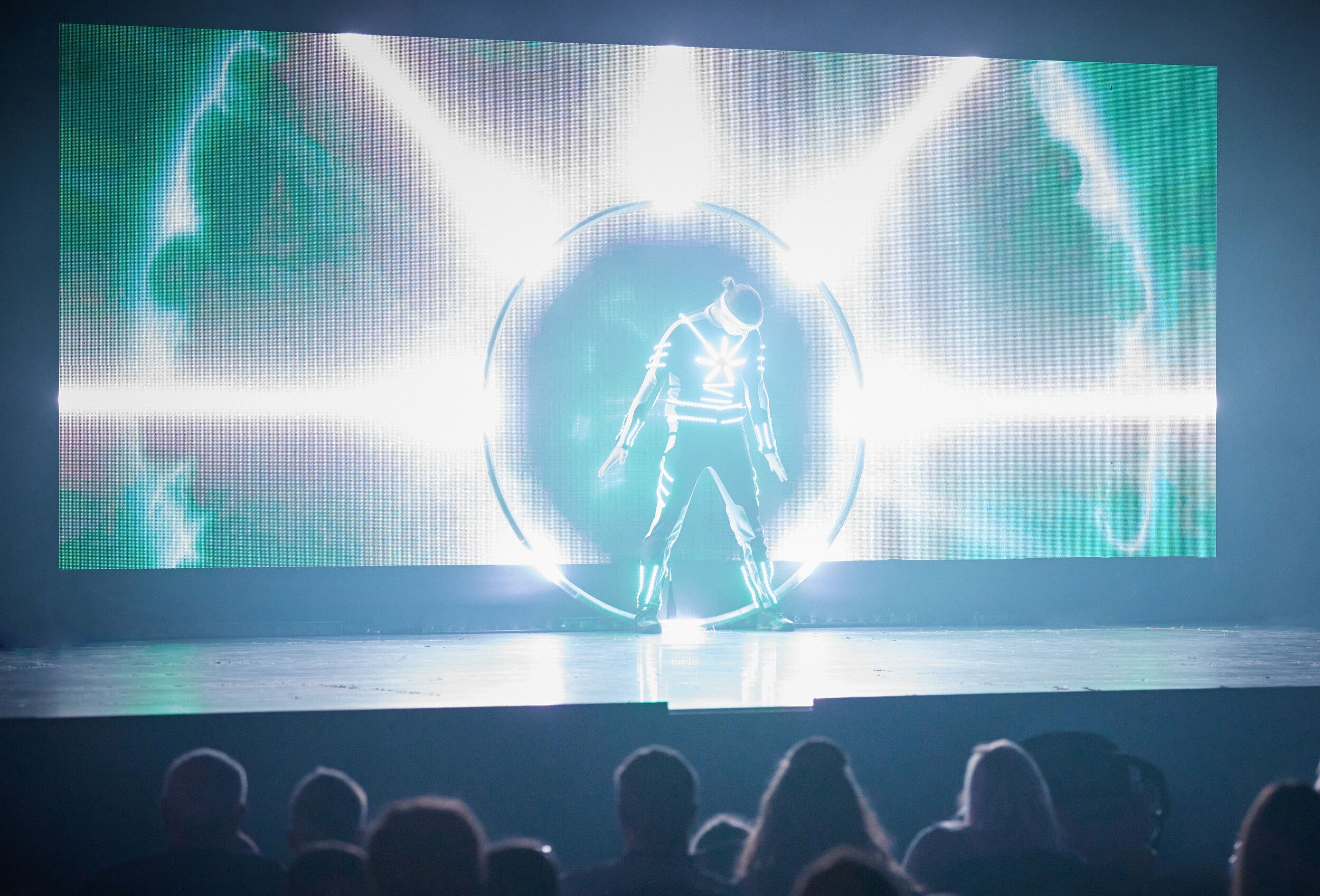 A man wearing an LED costume inside a steel ring on stage.