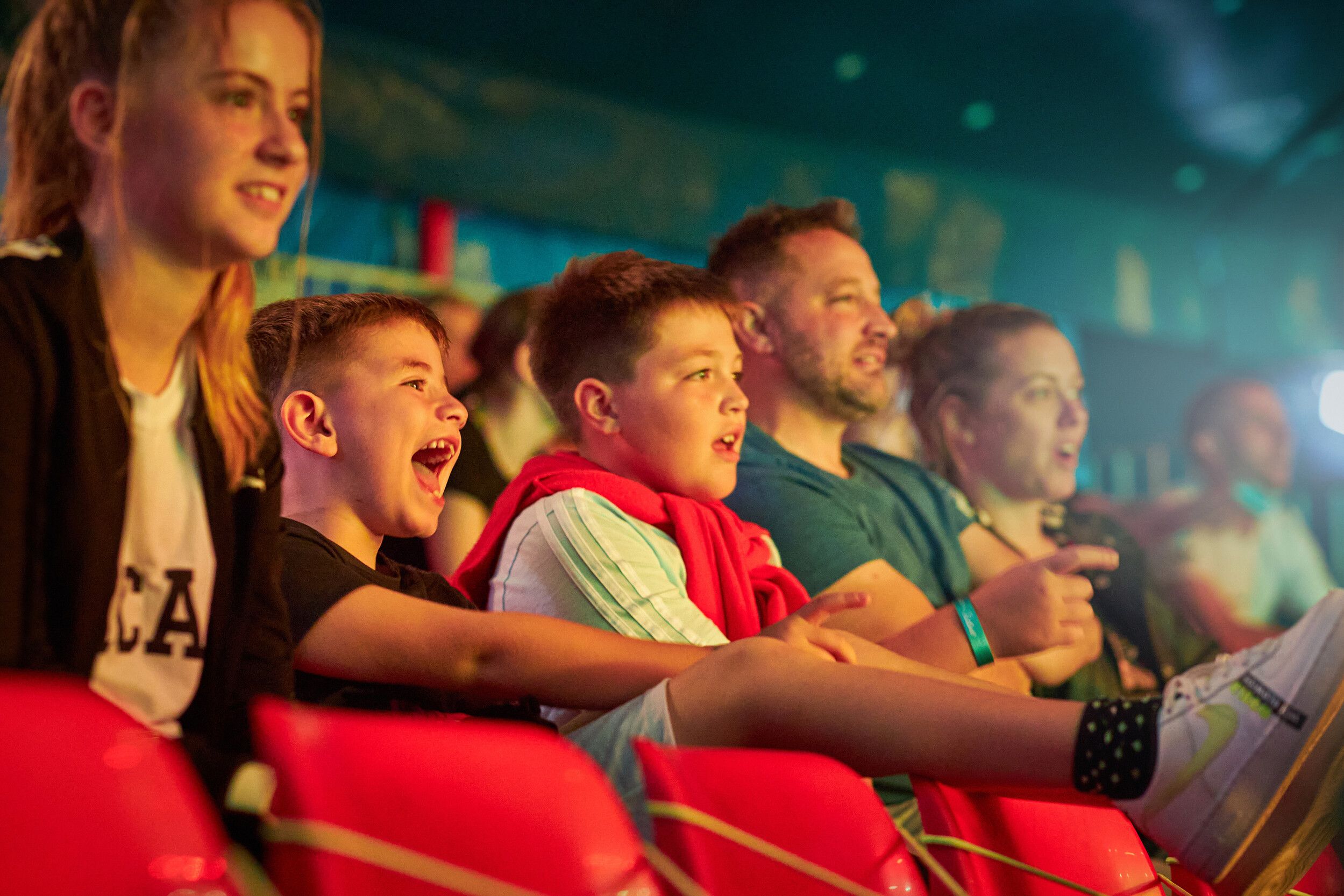 Three kids sitting at the audience while enjoying a show.