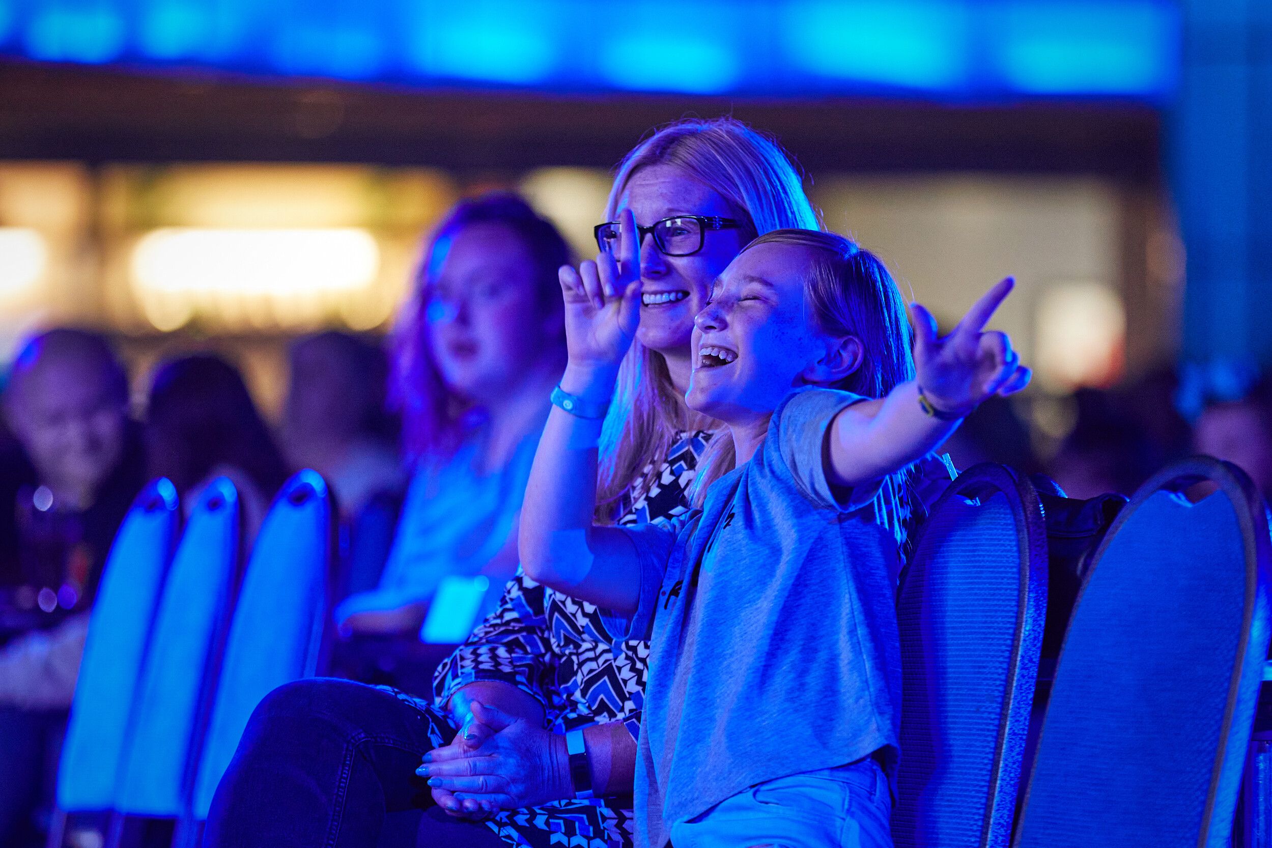 A little girl sitting down at the audience while dancing and watching a show.