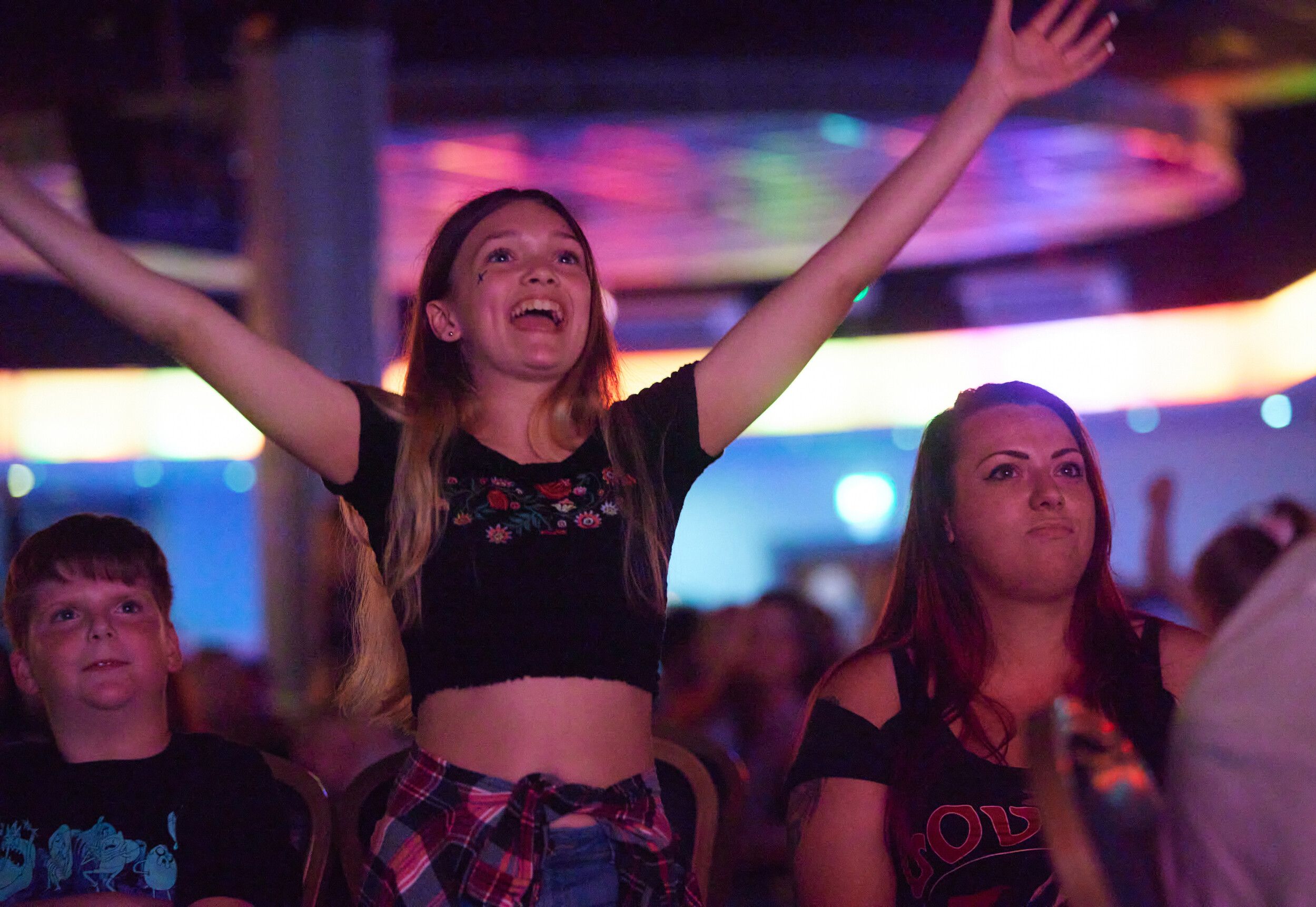 A girl raising her hands at the audience while watching a show.