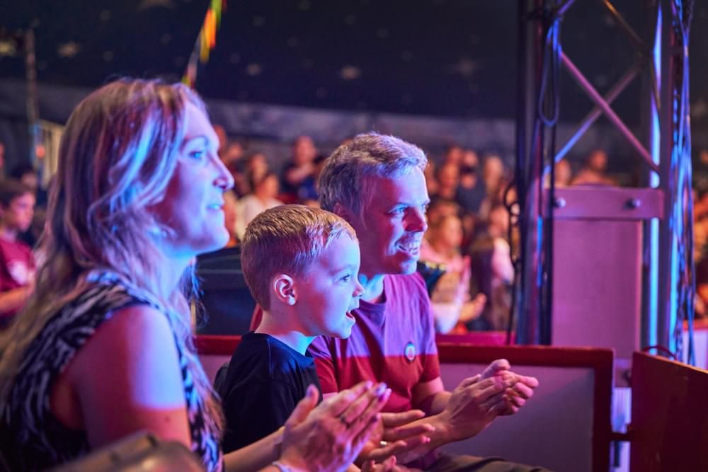 A family of three clapping their hands while watching a show.