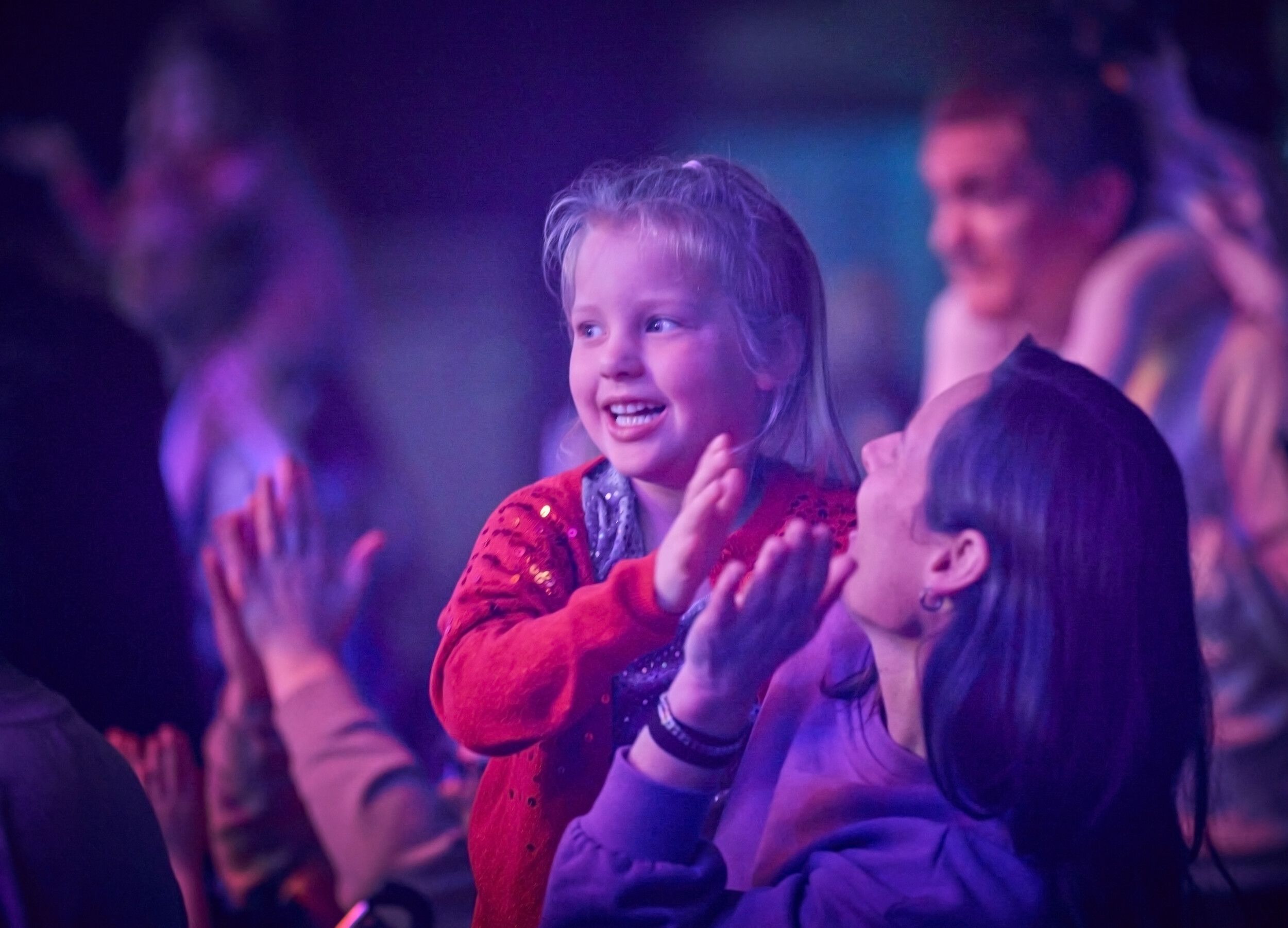 A mother carrying her daughter at the audience while enjoying a show.