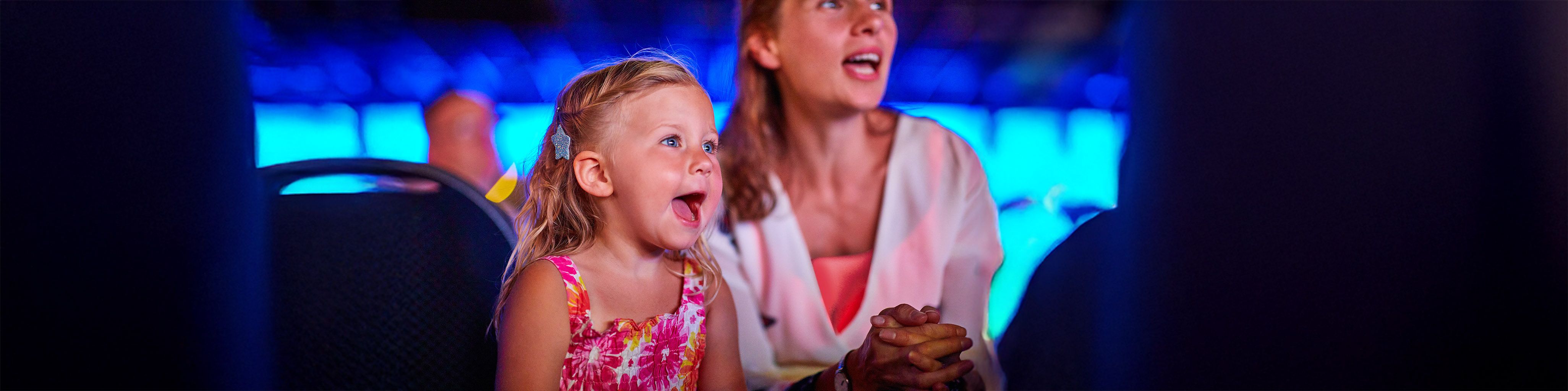 A mother and her young daughter happily watch a show together on a Butlin's break.