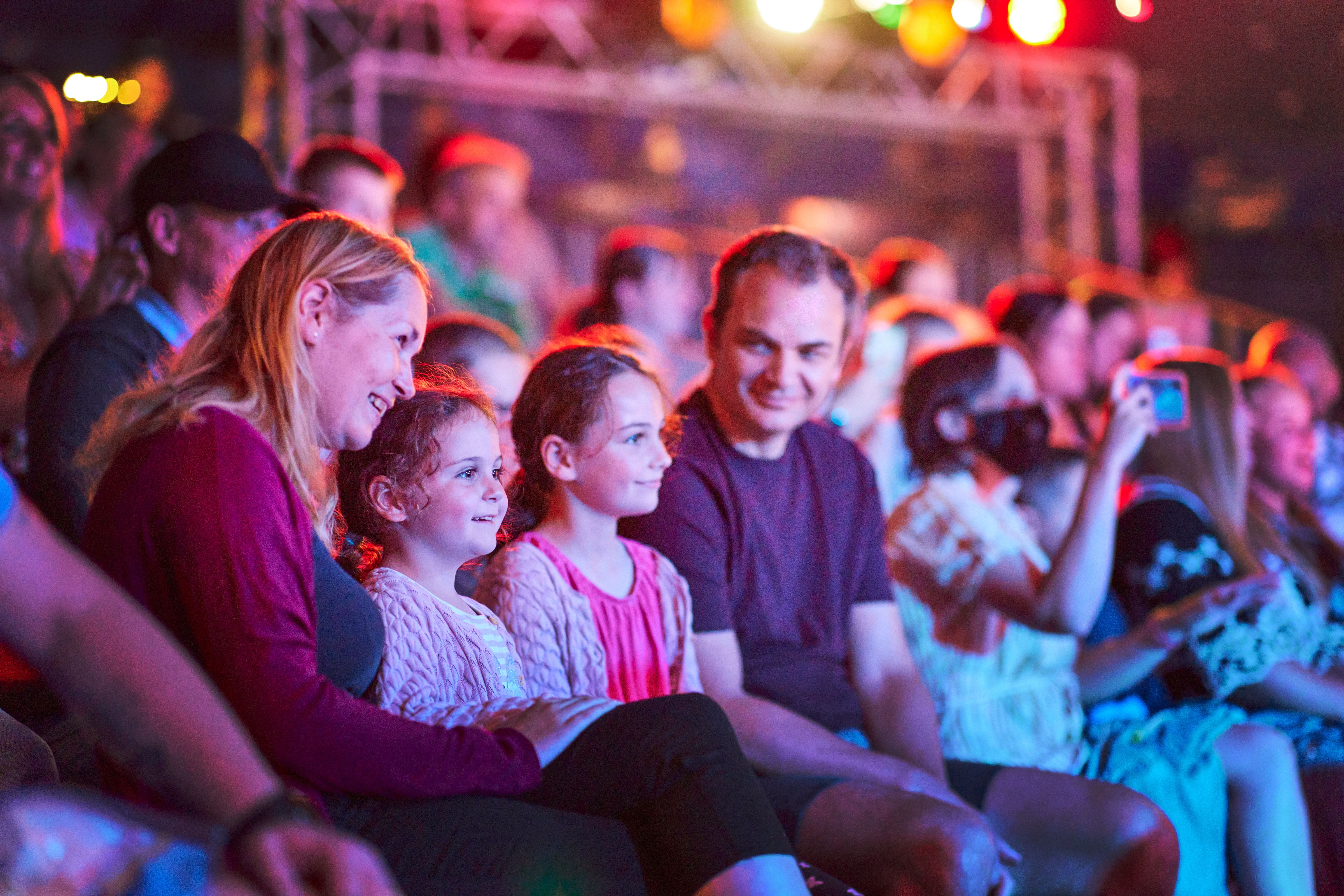 A family of four sitting down at the audience while watching a show.