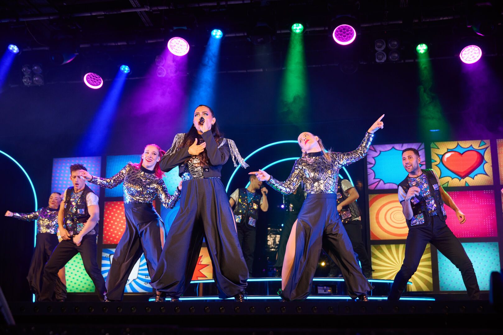 Performers stand on stage in formation as they sing and dance during the "ICONIC" live show at Butlin's.