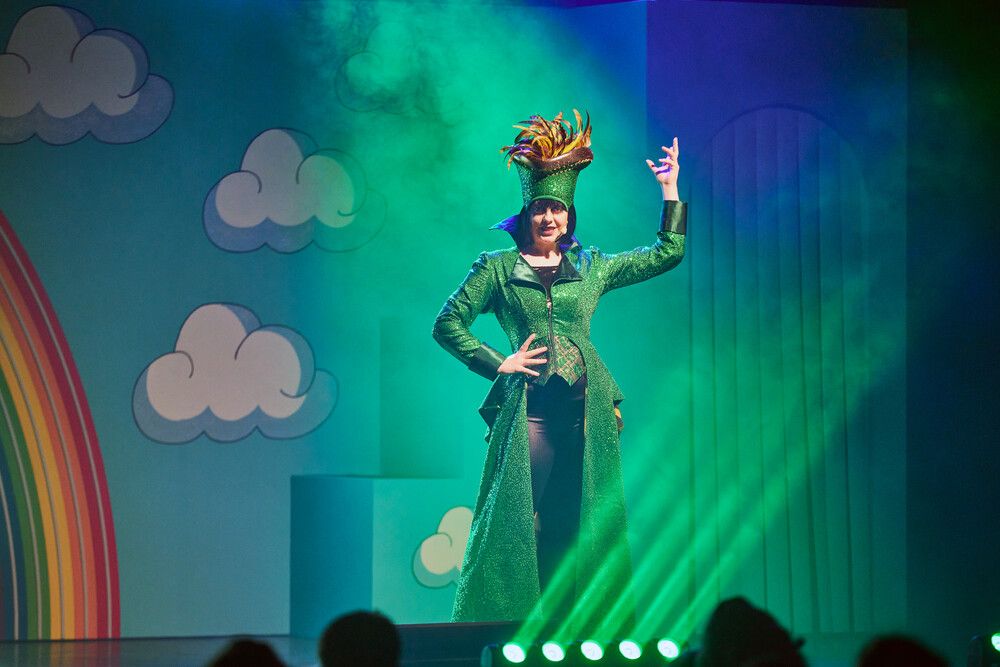 Jack & the Beanstalk character played with a woman in a green outfit performing on stage.
