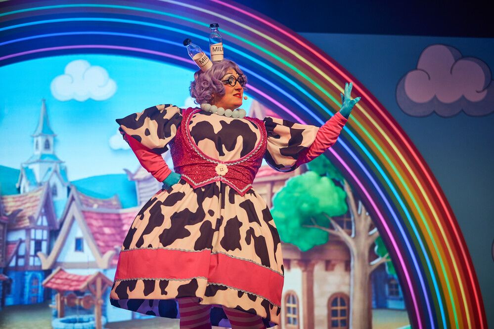 Jack & the Beanstalk character played with a woman while wearing a cow-themed costume on stage.