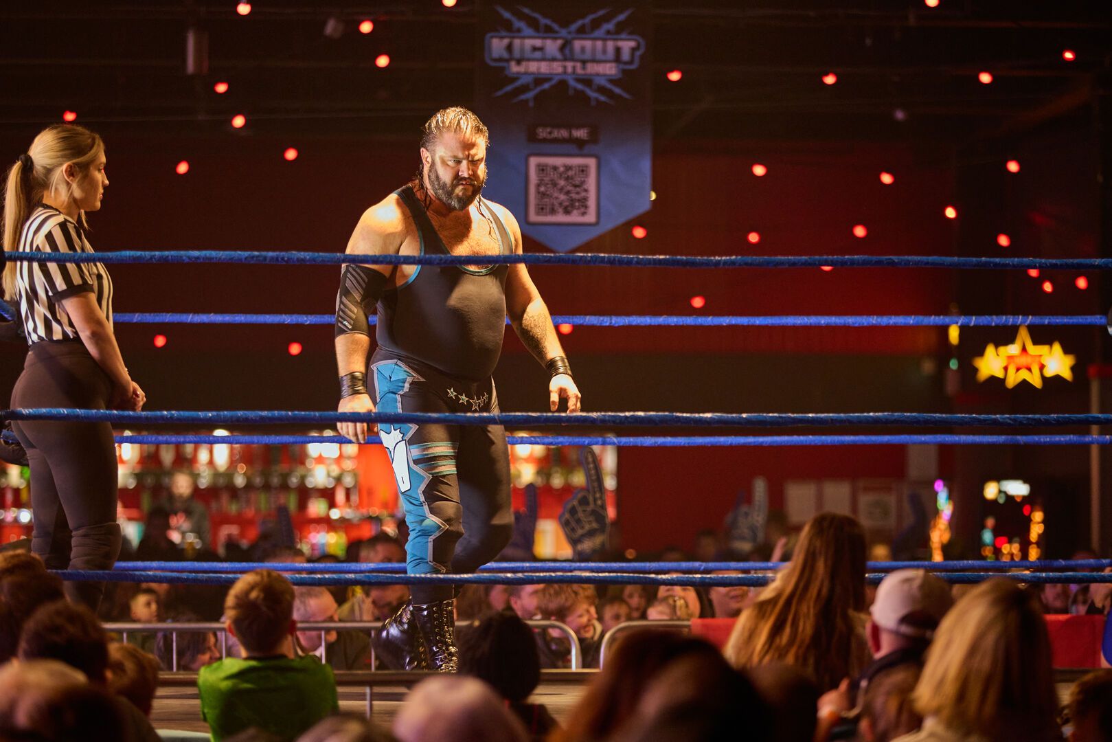 A wrestler stands in the ring, waiting his opponent as the audience watches on.