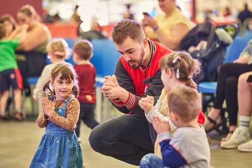A man in a red jacket playing with a group of kids.