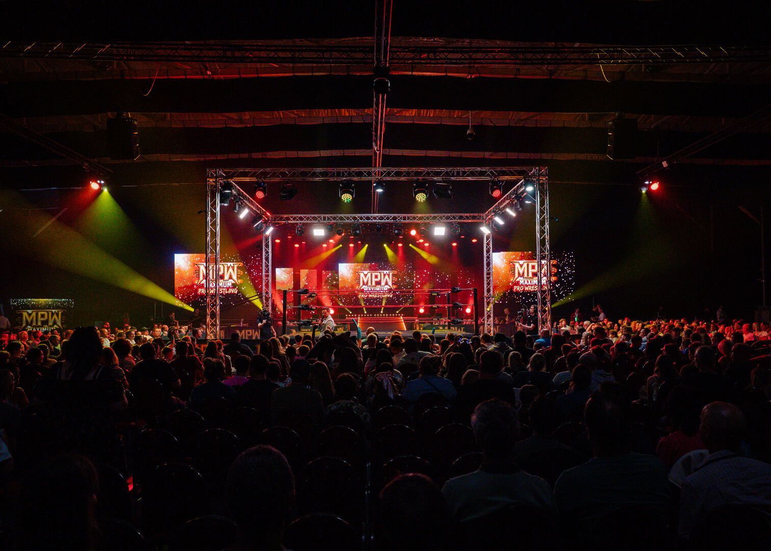 A wide-angle shot of a Maximum Pro Wrestling show at Butlin's. The ring is at the centre and the audience surrounds it on all sides.