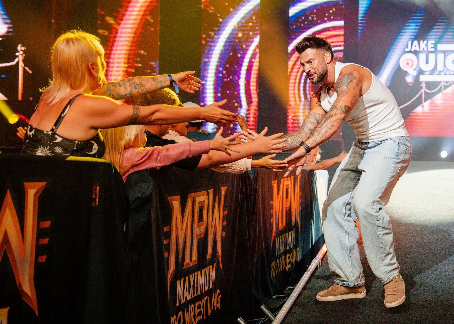 A wrestler walks along the audience who have their arms outstretched, as he greets each of them.