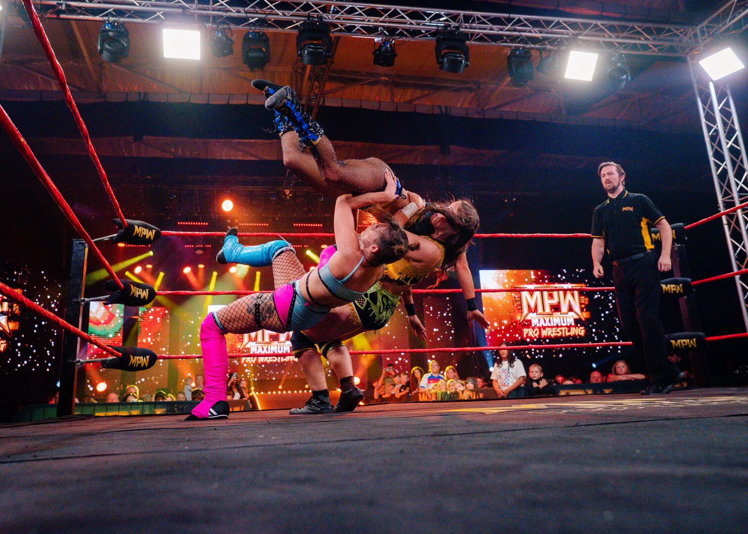 Three people wrestle in the ring during a Maximum Pro Wrestling live show at Butlin's.