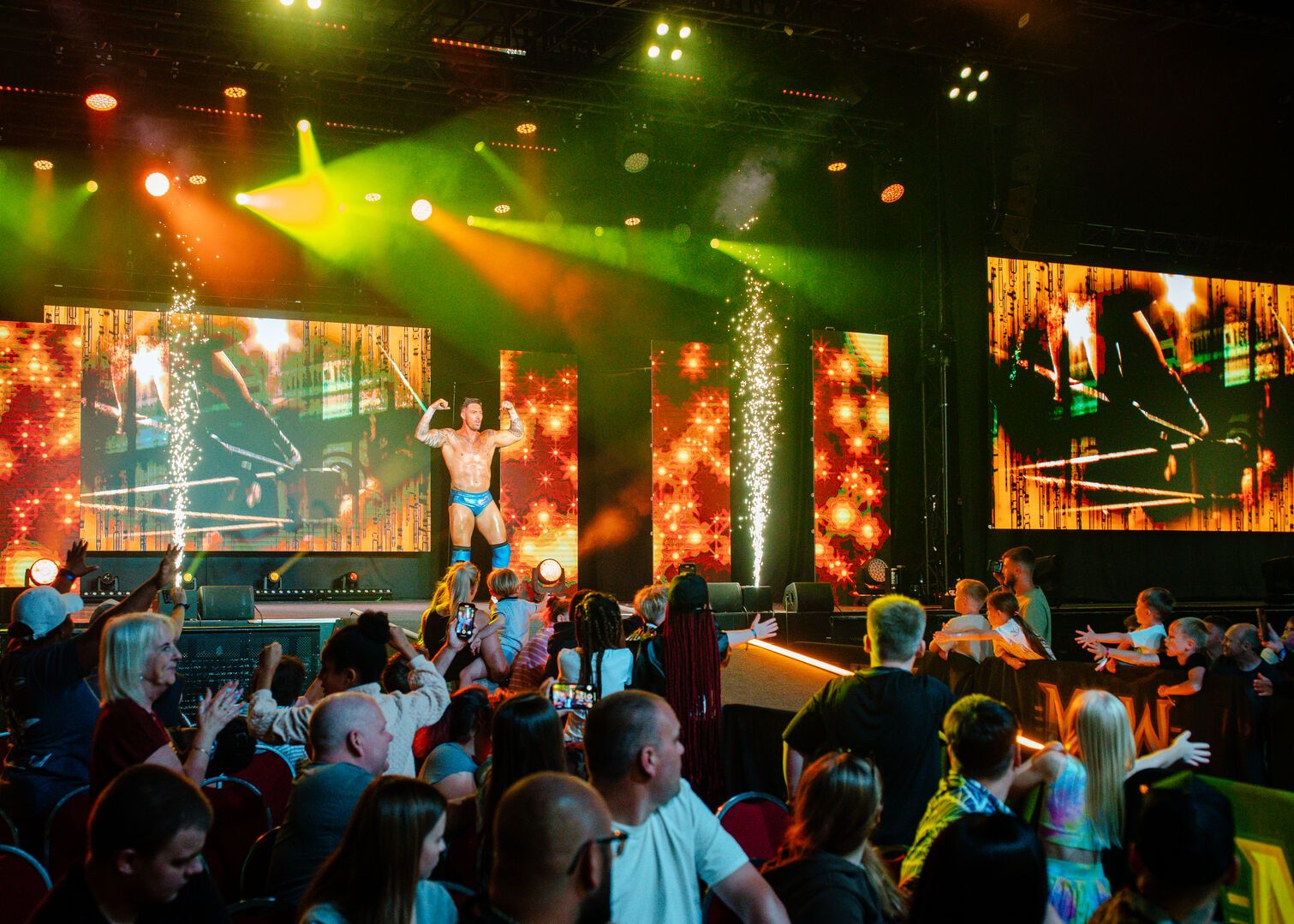 A wrestler flexes his arms as he walks down the ramp, towards the ring.