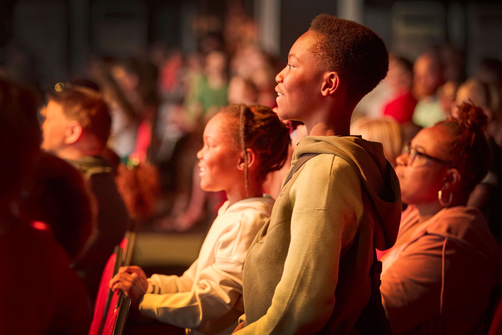 A close-up of a young boy in the audience watching the Maximum Pro Wrestling show with his sister.