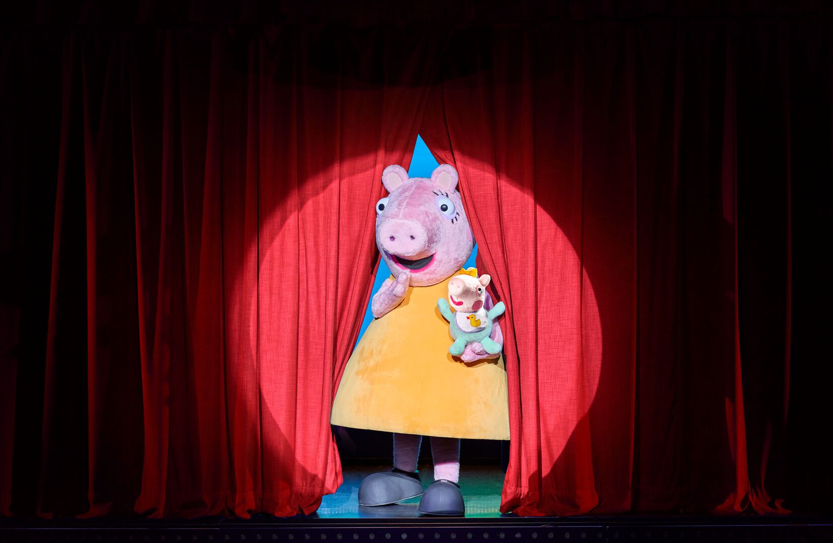 Mummy Pig steps onto stage with Evie in her arms.