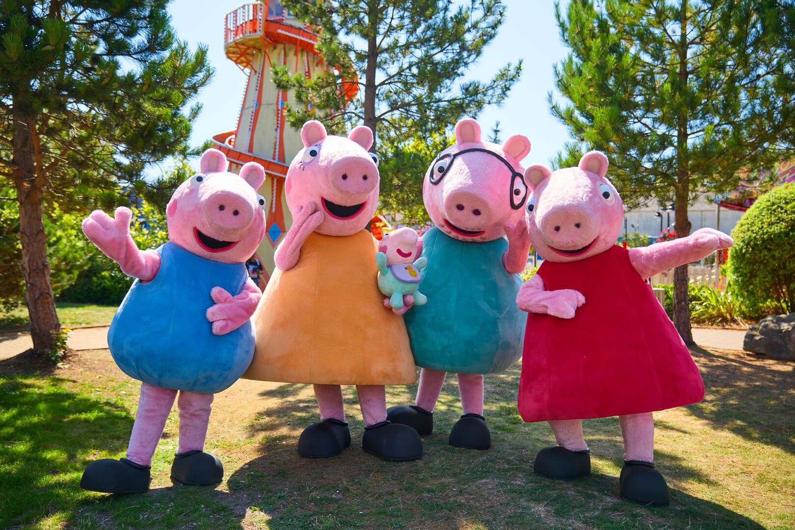 Peppa Pig and Evie pose for the camera with their family in front of the fairground at Butlin's.