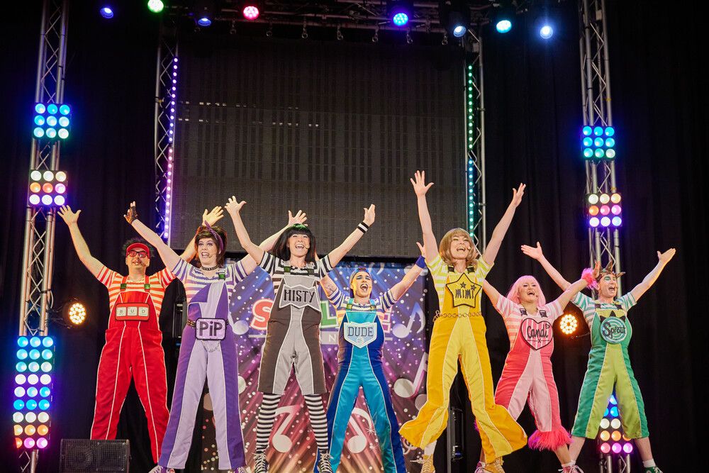 Going for Gold members wearing colourful outfits while performing on stage.