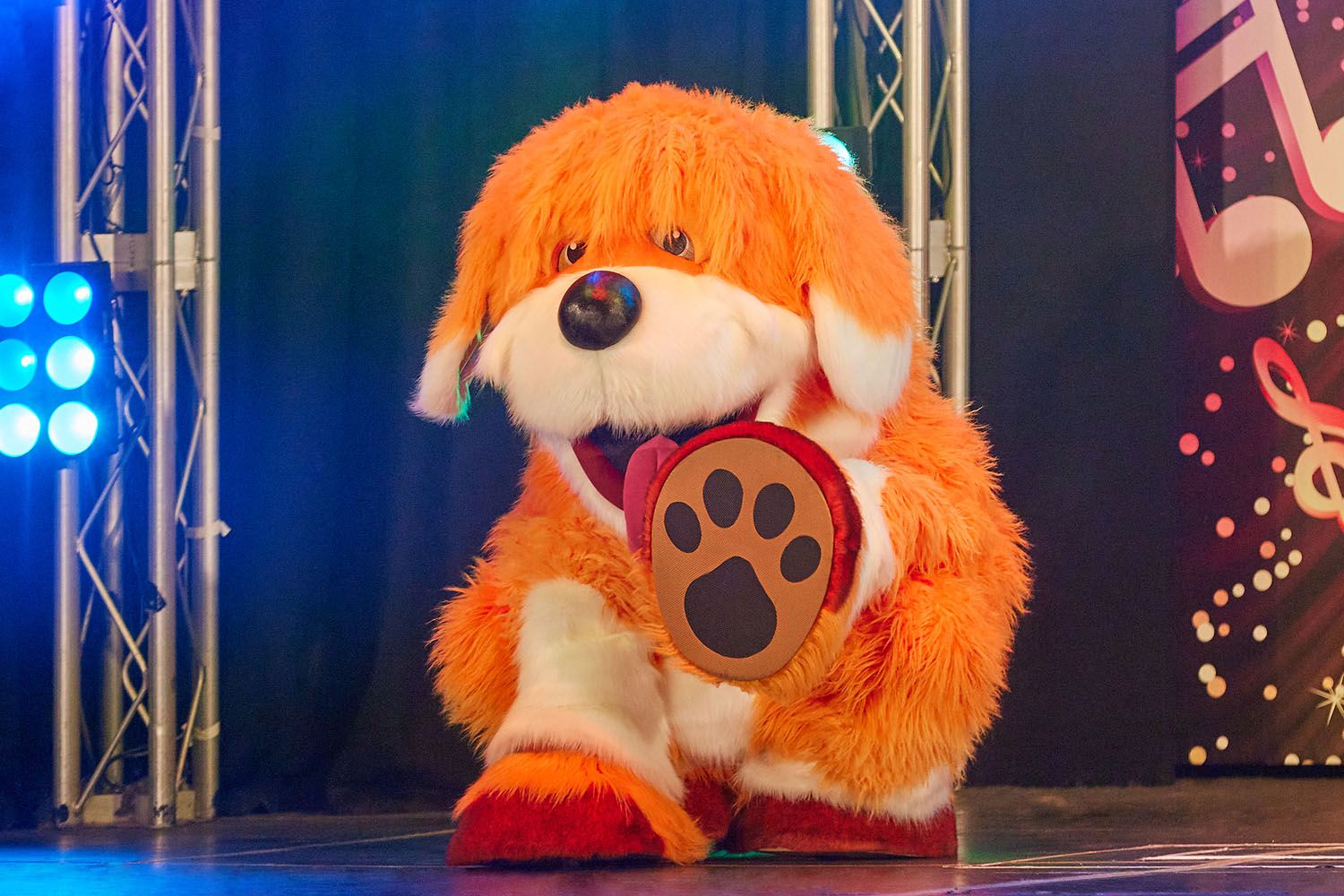 A Rainbow the dog mascot presenting on stage.