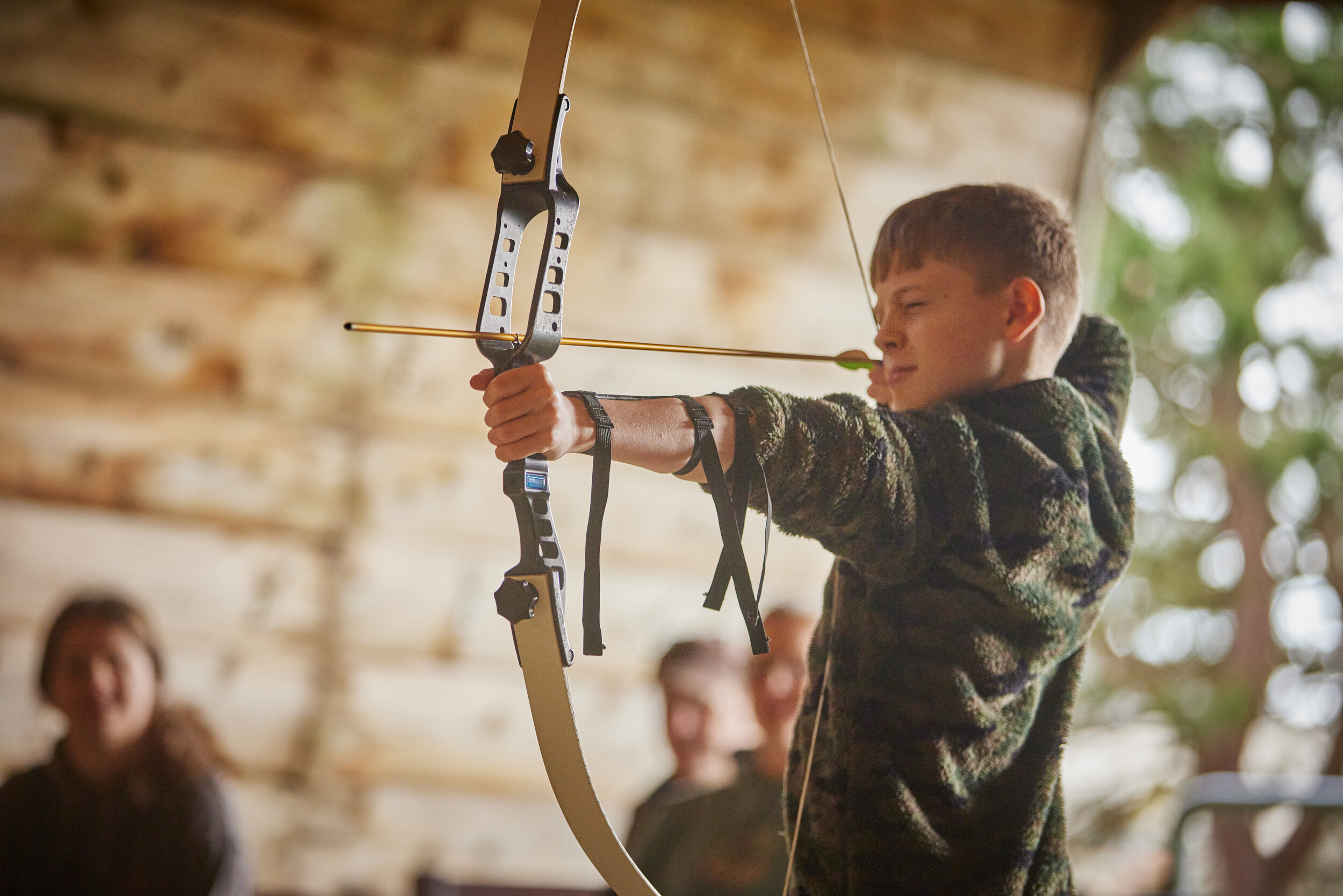 A boy aiming with a bow and arrow.