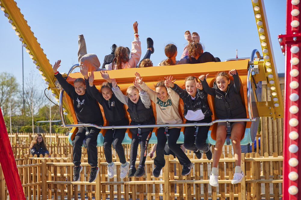 A group of children enjoying the Super Swing fairground ride.
